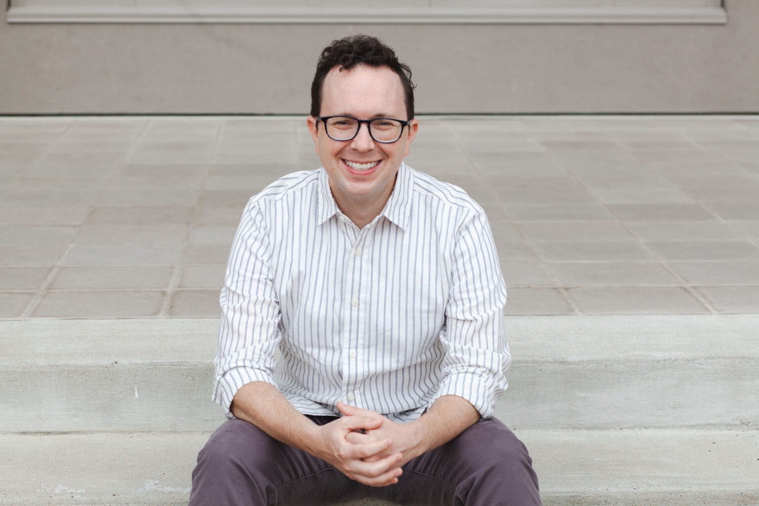 Eric Detweiler sitting on steps and smiling.